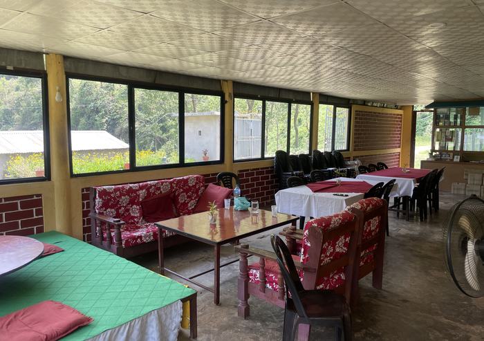 The indoor dining room: laid tables, cushioned benches and a long run of windows onto the trees