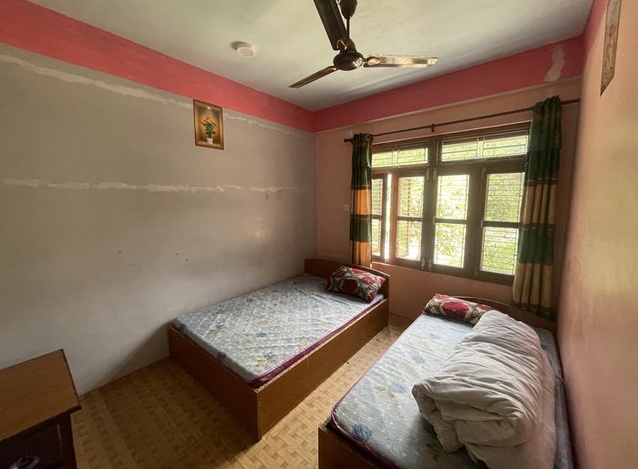 A twin room with two single beds, a ceiling fan and a large window